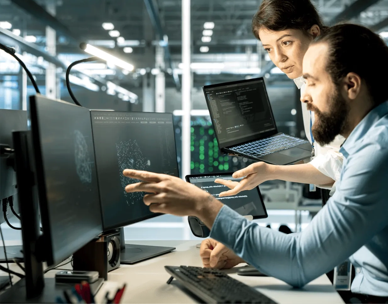 Two colleagues collaborate at a computer, reviewing API workflows and system integration details.