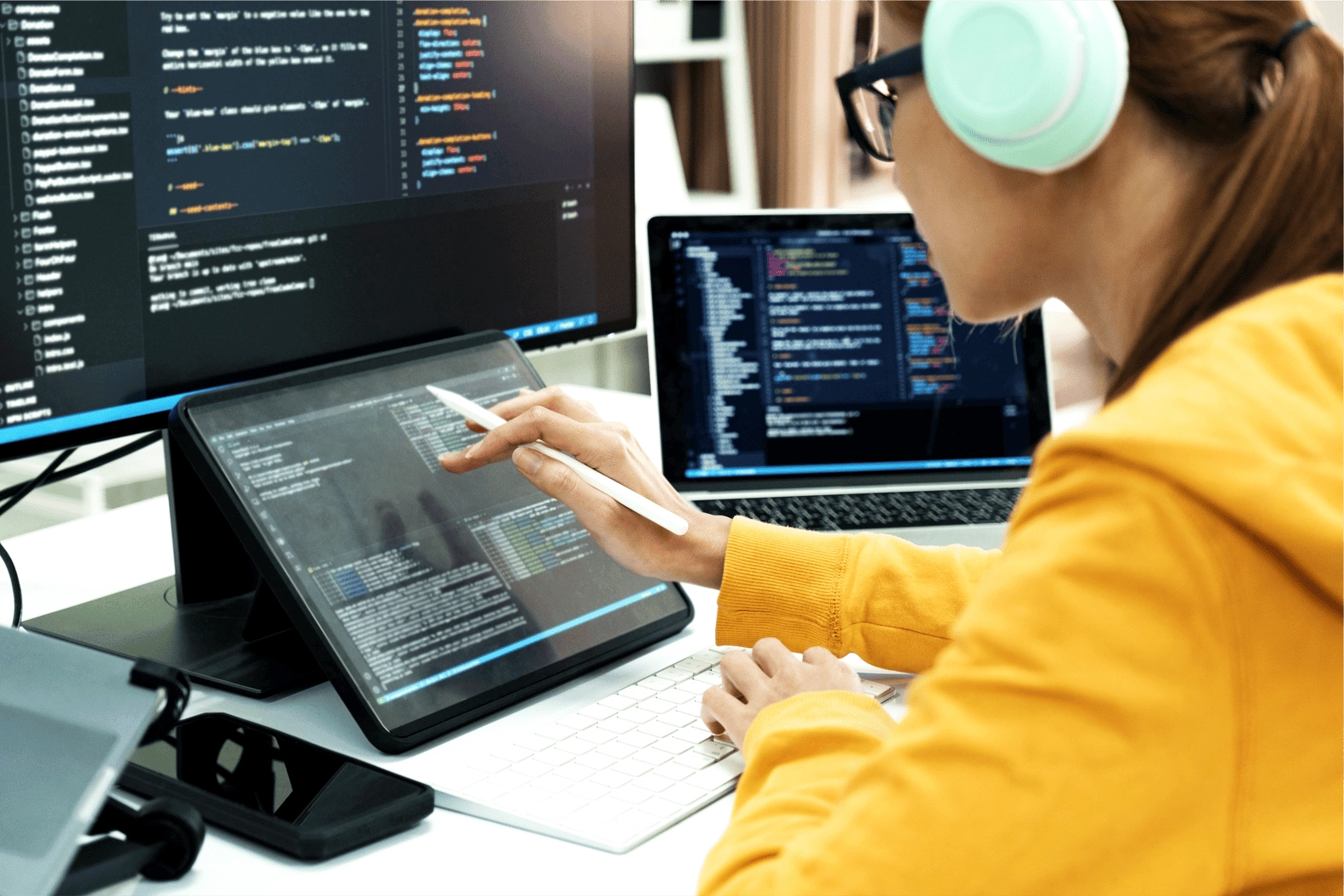 Programmer looking at a screen and her tablet