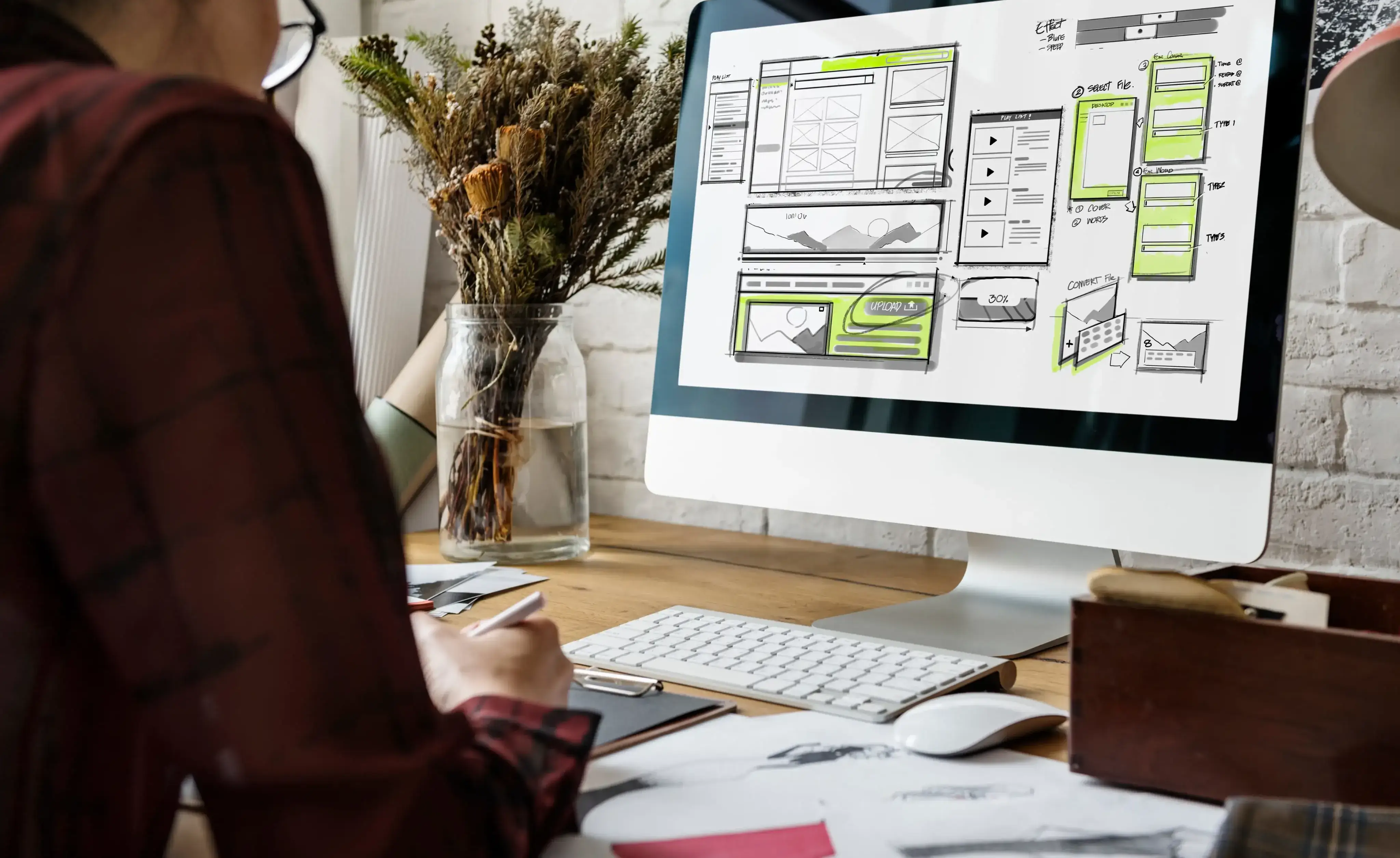 A person designing on paper and a computer.